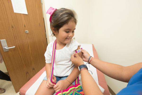 Child smiling as a nurse puts a bandage on their arm