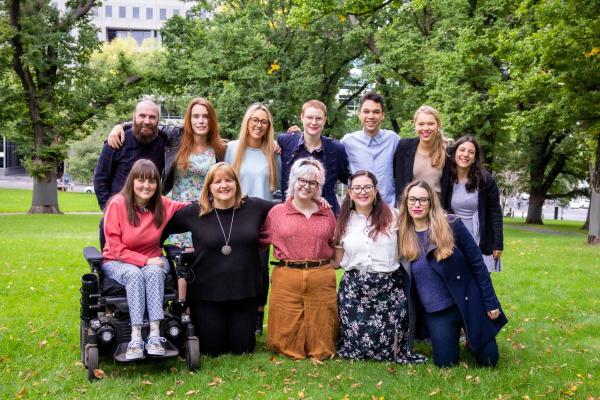 12 people smiling together in a park