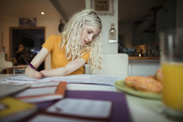 A young person sitting at a table looking at some papers. She is an amputee.