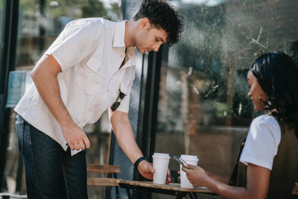 Two young people outside a cafe with coffees