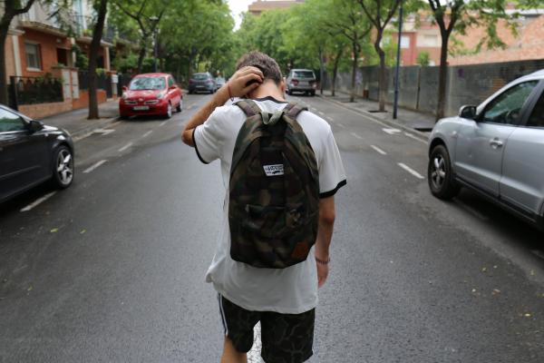 Back of a young person walking down the street and feeling down