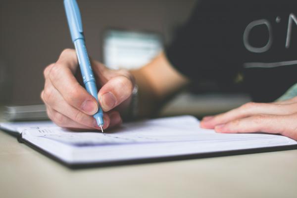 Close up of a hand writing a list in a notebook