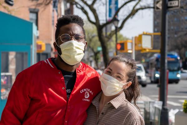 Two young people standing together wearing masks and smiling