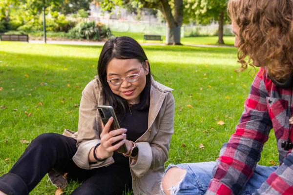 A young person with glasses looking at her phone
