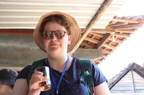 Lilli Rose wearing mirrored sunnies holds a drink and smiles gently at camera